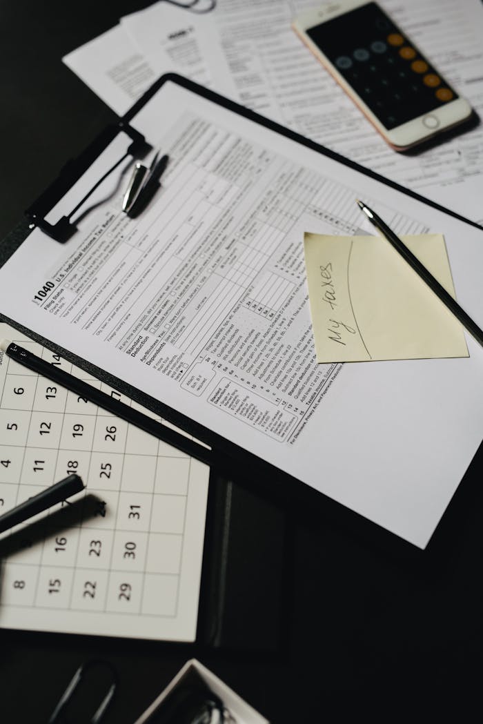 SERVICIOS Close-up view of a neatly organized desk with tax forms, calculator, and stationery for financial planning.