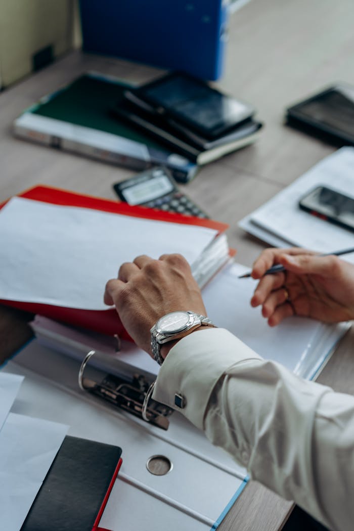 ACERCA DE Businessman's hands organizing paperwork and files on a busy office desk.